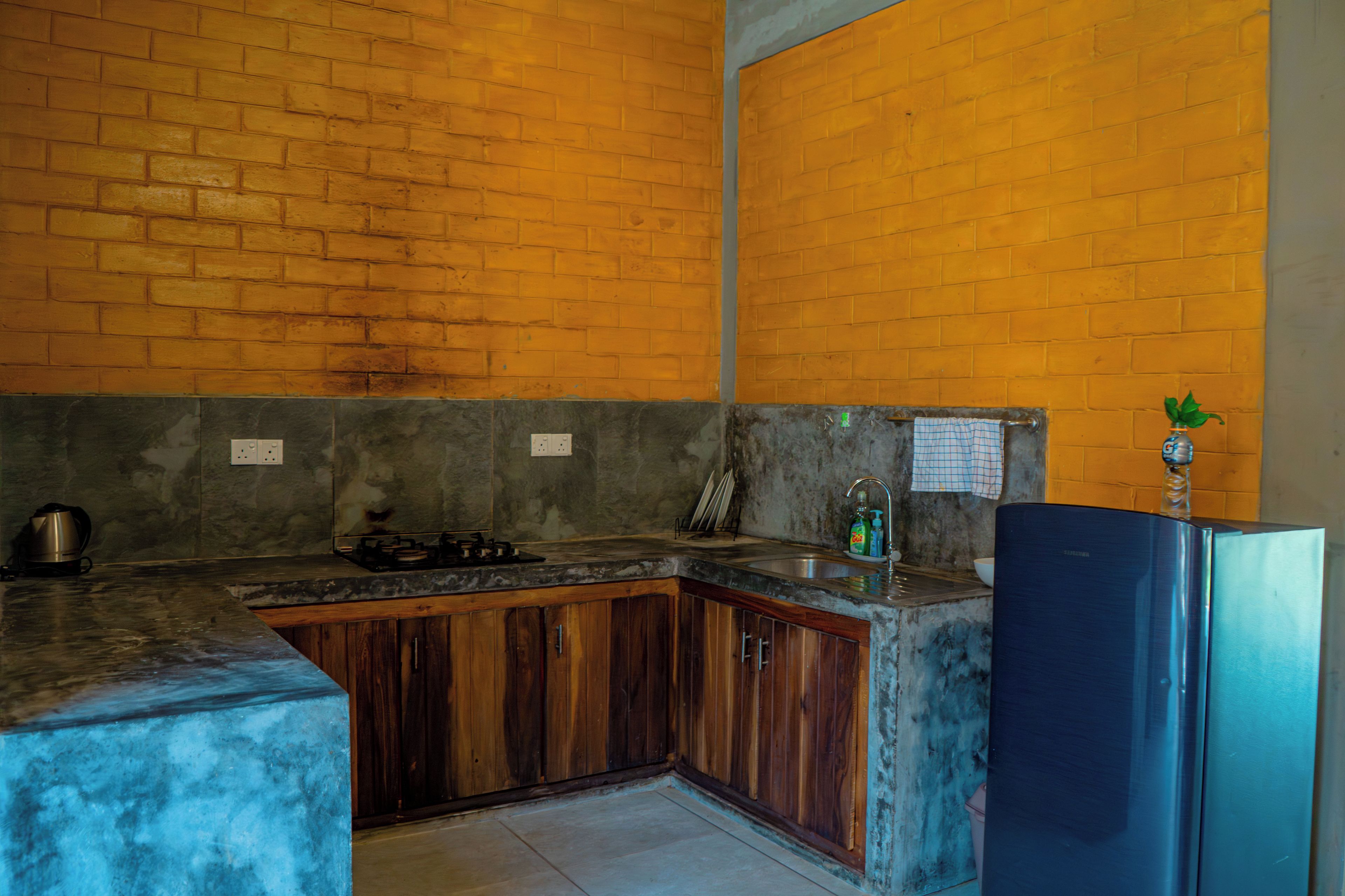 Una cocina con pared de ladrillo, refrigerador de acero inoxidable y un lavamanos.