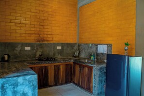 Een keuken met een bakstenen muur, een roestvrijstalen koelkast en een gootsteen.