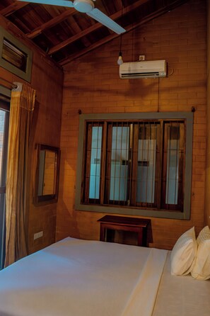 A room with a bed, a window with bars, a ceiling fan, and an air conditioning unit. - Fort & Beach Retreat (Galle)