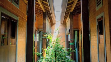 Un pasillo con un árbol central, vigas de madera y paredes de ladrillo.