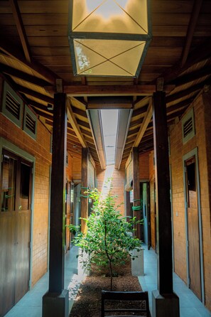 A corridor with a central tree, wooden beams, and brick walls. - Fort & Beach Retreat (Galle)