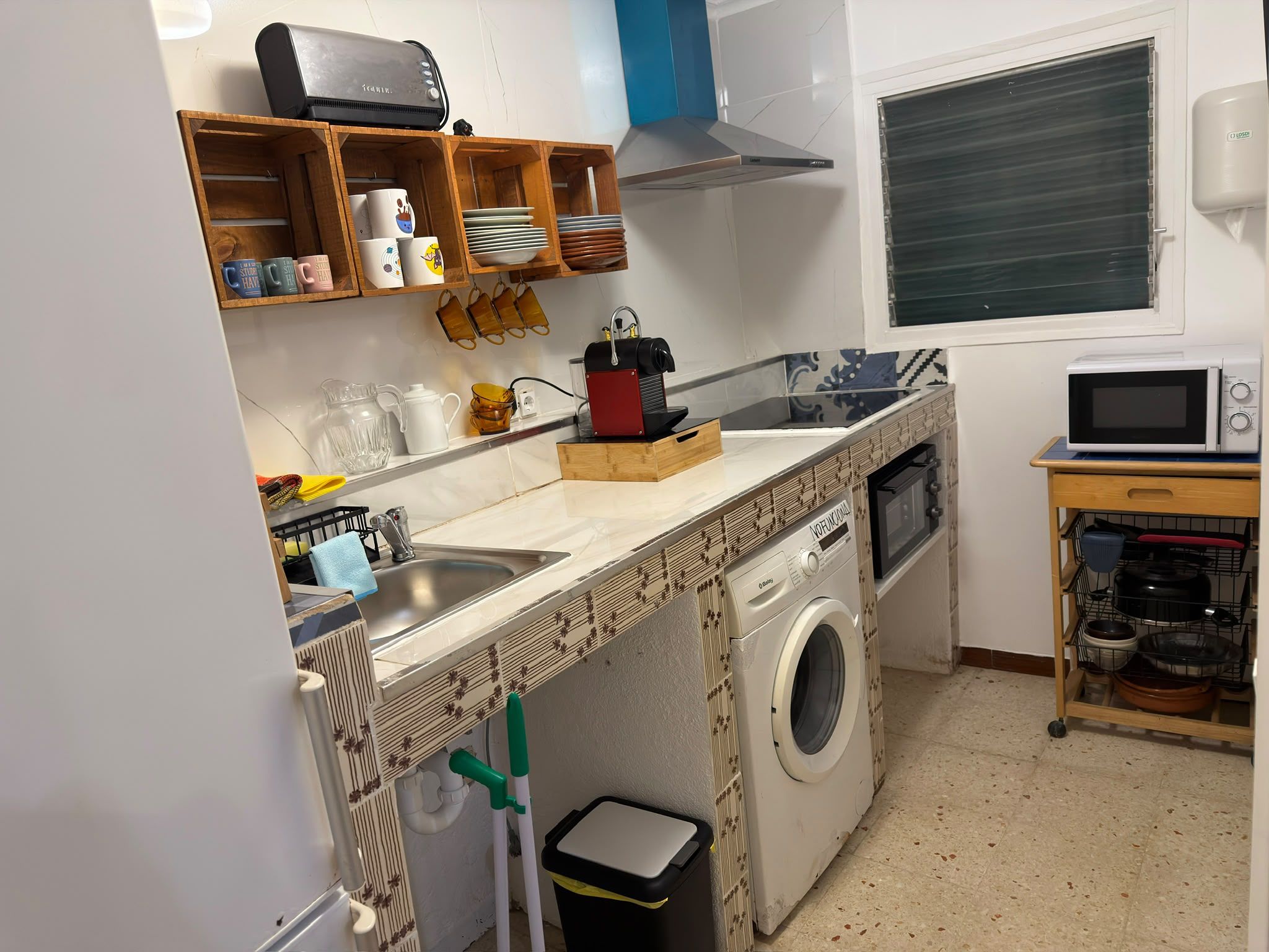 A compact kitchen with a washing machine, a microwave, and a sink.
