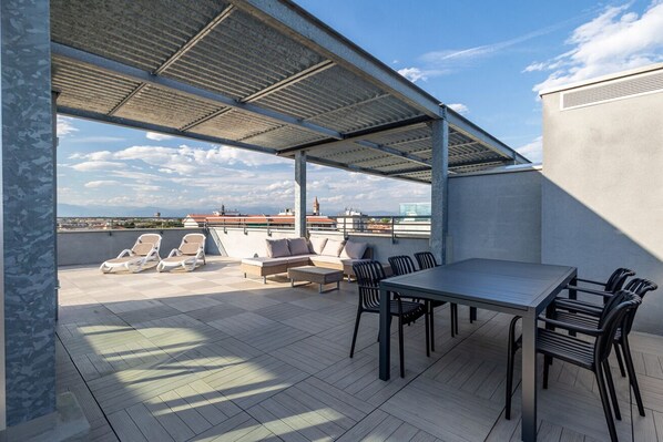 An outdoor patio area with a covered seating area, a table, and chairs.