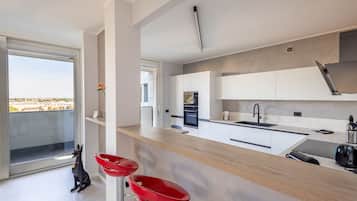 Una cocina moderna con un ventanal grande, un perro y taburetes rojos.