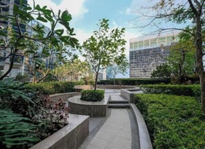 Ein angelegter Innenhof mit Wegen, einem zentralen Baum und modernen Gebäuden im Hintergrund.