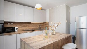 Eine moderne Küche mit weißen Schränken, einer Holz Arbeitsplatte, einem Einbauofen, einer Spüle und einem Edelstahl-Kühlschrank.