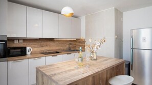A modern kitchen with white cabinets, a wooden countertop, a built-in oven, a sink, and a stainless steel refrigerator. - Villa Franika by Villas Guide (Medulin)