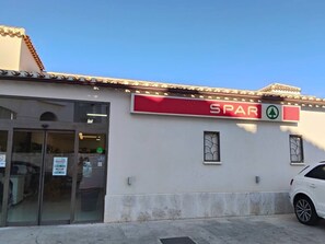Un bâtiment avec une enseigne rouge portant l’inscription « SPAR » et un symbole de flèche verte.