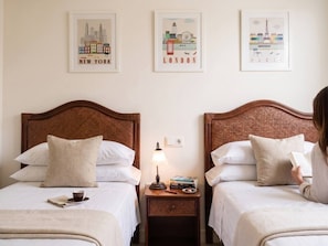A hotel room with two beds, a nightstand with a lamp, a book, and a cup. - The Rahm Residence | Golf Retreat & Private Terrace (Murcia)