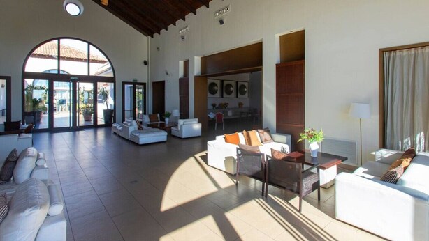 A spacious lobby with a high ceiling, a central seating area, and a view through a glass door leading to an outdoor area. - El Valle Golf Residence | Private Terraces & Pools (Murcia)
