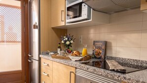 A kitchen with a stainless steel refrigerator, a microwave, a stove, and a countertop with a tray of food and a book. - El Valle Golf Residence | Private Terraces & Pools (Murcia)