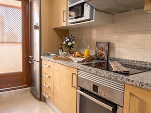 Eine Küche mit einem Edelstahl-Kühlschrank, einer Mikrowelle, einem Herd und einer Arbeitsplatte mit einer Schale Essen und einem Buch.