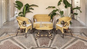 A room with a patterned floor, a central seating area with chairs, and large green plants. - Colombo Suites, the stunning Ligurian Riviera: a taste of nature and relaxation (Lavagna)