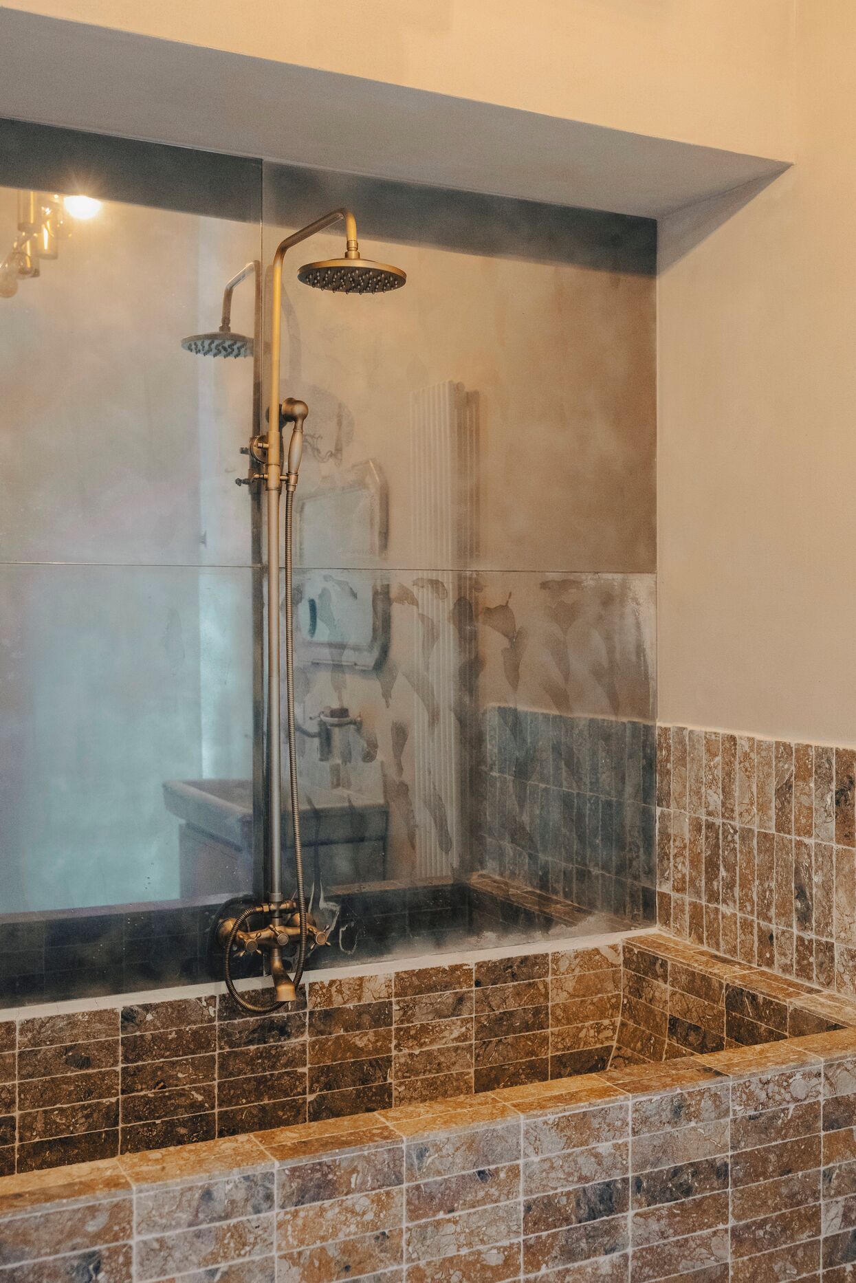 Une salle de bain équipée d’une baignoire, d’une douche et d’un espace de douche séparé par des parois en verre.
