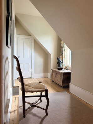 A room with a wooden chair, a white door, a wooden dresser, and a window with curtains. - Heart of Nova Scotia’s South Shore - Curated Luxury in a Landmark Home (Mahone Bay)