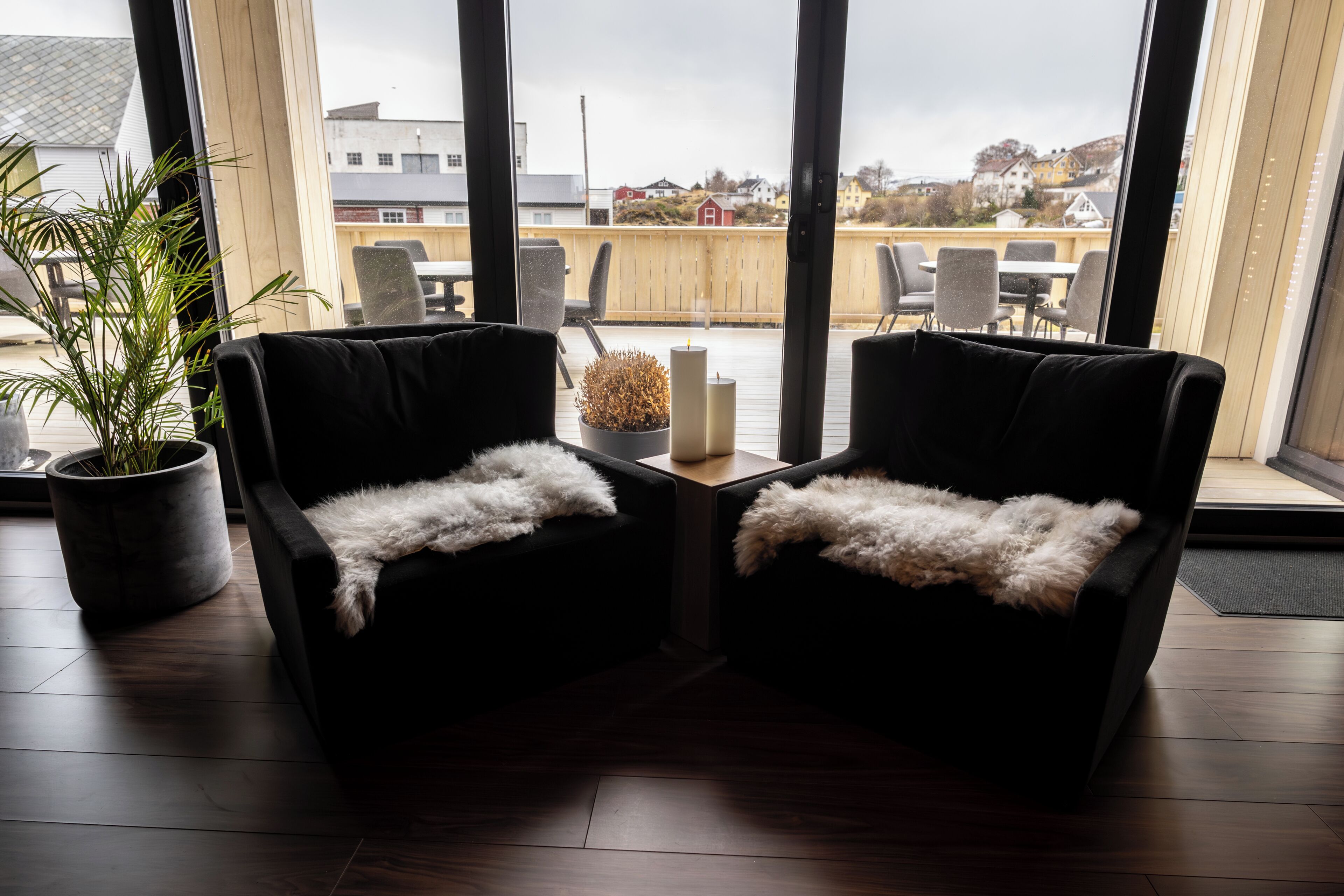 A room with two black armchairs, a small table with candles, and a potted plant.