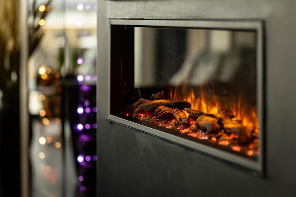 Ein Kamin mit sichtbaren Holzscheiten und lodernden Flammen.