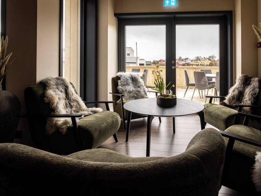 Un rincón acogedor con sillones cómodos y una mesa redonda, con vistas a una terraza con mobiliario exterior.