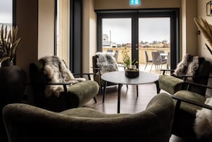 Un rincón acogedor con sillones cómodos y una mesa redonda, con vistas a una terraza con mobiliario exterior.