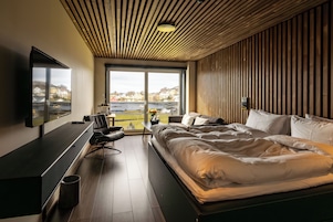 Un dormitorio moderno con una cama grande, un escritorio y vistas a un río y casas.
