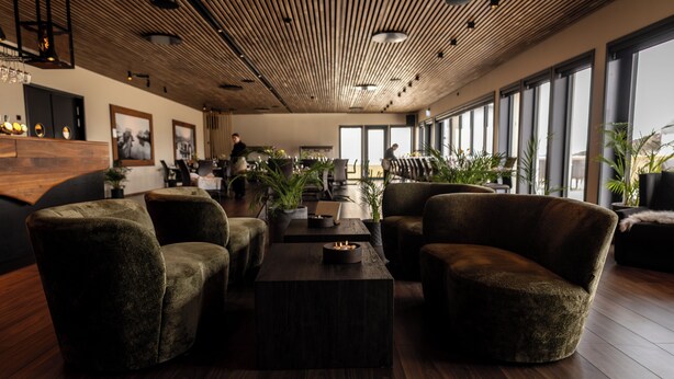 A modern interior with wooden flooring, a central coffee table, and seating arrangements. - Rosenlund Hamn (Sande)