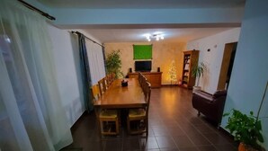 A dining area with a long wooden table and chairs, a television, and a Christmas tree. - Vila Alex (Tășnad)
