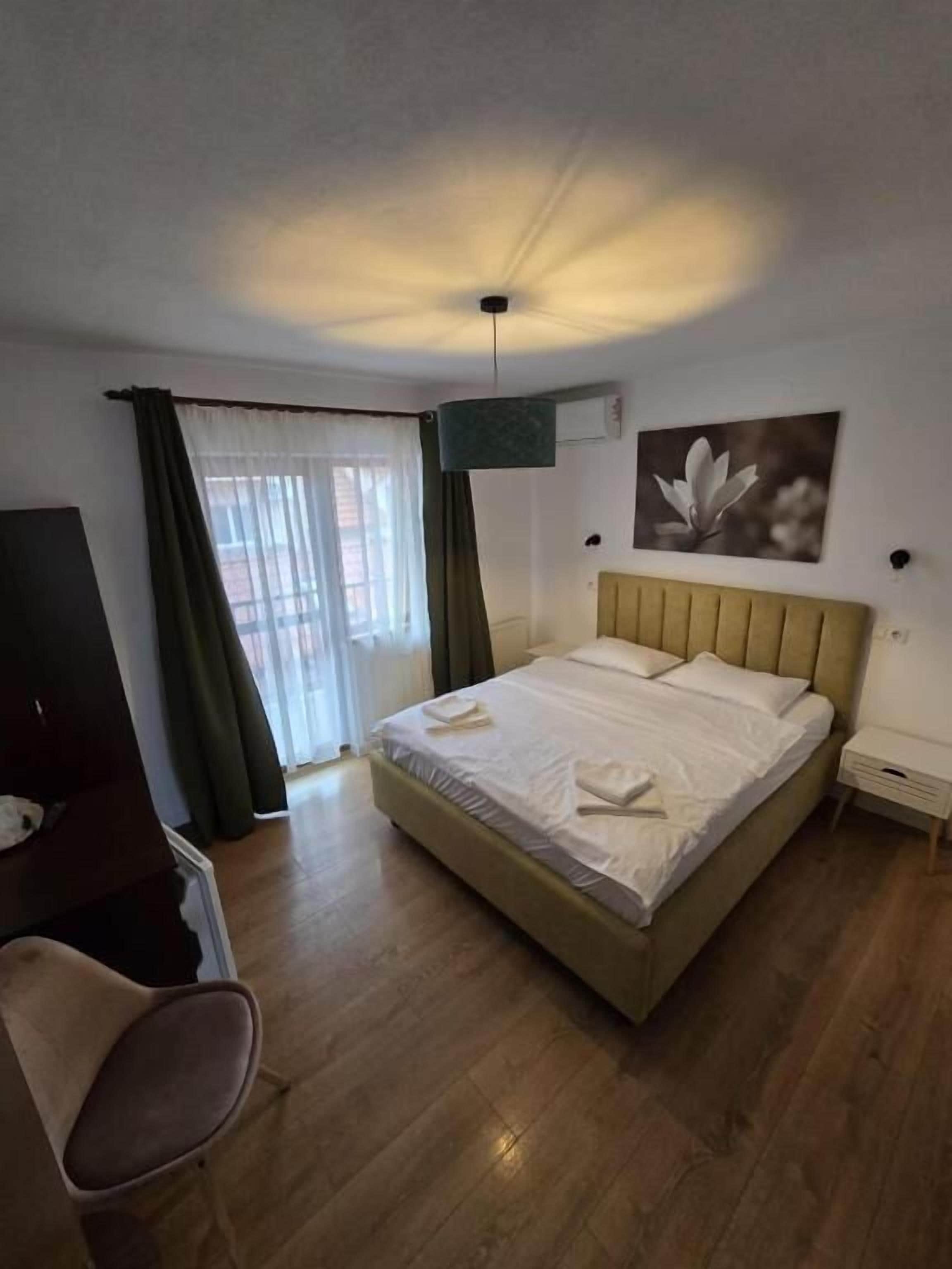 Een hotelkamer met een bed, een bureau, een stoel en een raam met gordijnen.