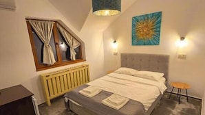 A bedroom with a bed, a window with curtains, a radiator, a wall-mounted light fixture, and a painting. - Vila Alex (Tășnad)