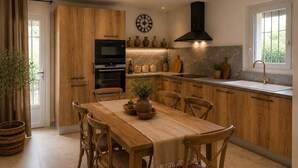 Una cucina moderna con mobili in legno, forno integrato e un ampio tavolo da pranzo.