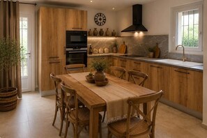 Eine moderne Küche mit Holzschränken, einem eingebauten Ofen und einem großen Esstisch.