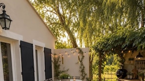 Un patio in legno con vasca idromassaggio, posti a sedere all'aperto e luci decorative.