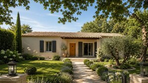 Una casa con tetto in tegole, una porta d'ingresso e un giardino curato con un vialetto in ghiaia che conduce all'ingresso.