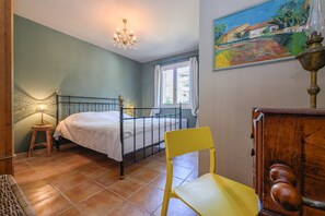 A bedroom with a bed, a chair, a lamp, a window, and a painting on the wall. - Holiday Home 'L’Isclèze' with Mountain View, Wi-Fi and Air Conditioning (Mollans-sur-Ouvèze)