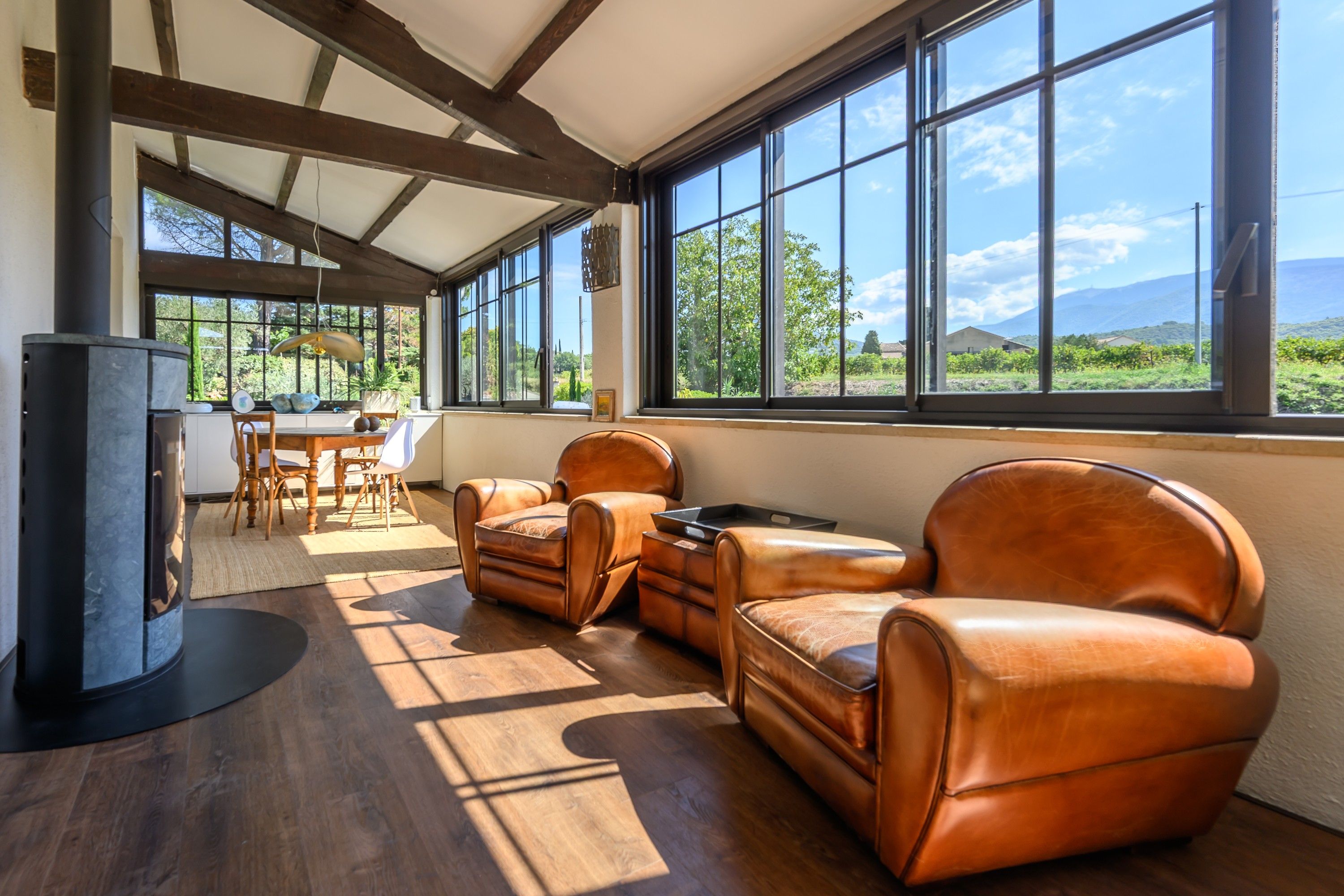 A spacious room with a large window, a fireplace, leather seating, and a dining area.