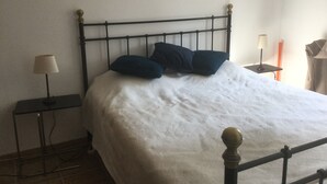 A bed with a metal frame, two pillows, a white bedsheet, a bedside table with a lamp, and a wall-mounted lamp. - Holiday Home 'L’Isclèze' with Mountain View, Wi-Fi and Air Conditioning (Mollans-sur-Ouvèze)