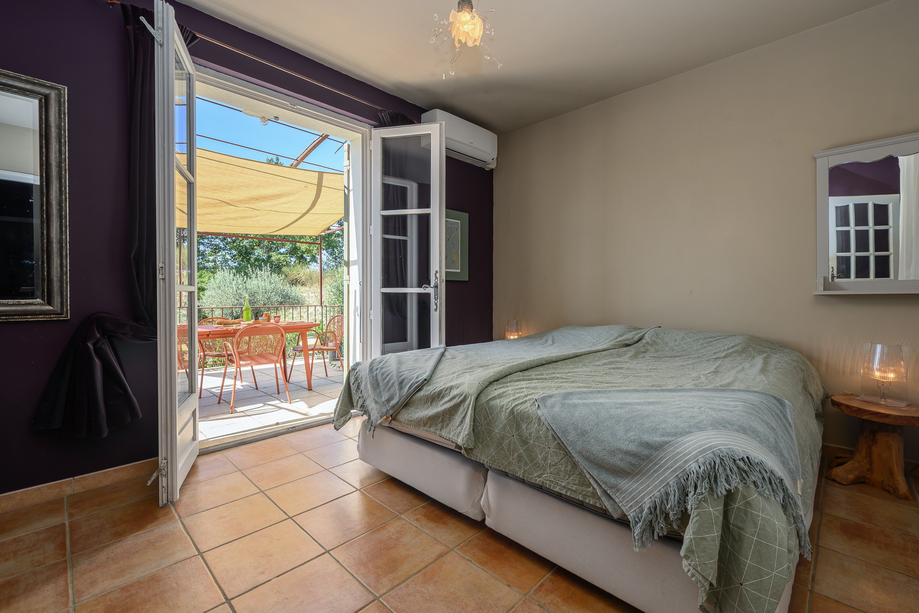 Quarto com cama, janela e porta que dá para uma varanda.