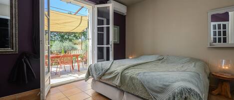 A bedroom with a bed, a window, and a door leading to a balcony.