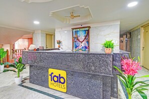 Un mostrador de recepción de hotel con encimera de mármol, ventilador de techo y un letrero que dice 'fab hotels'.