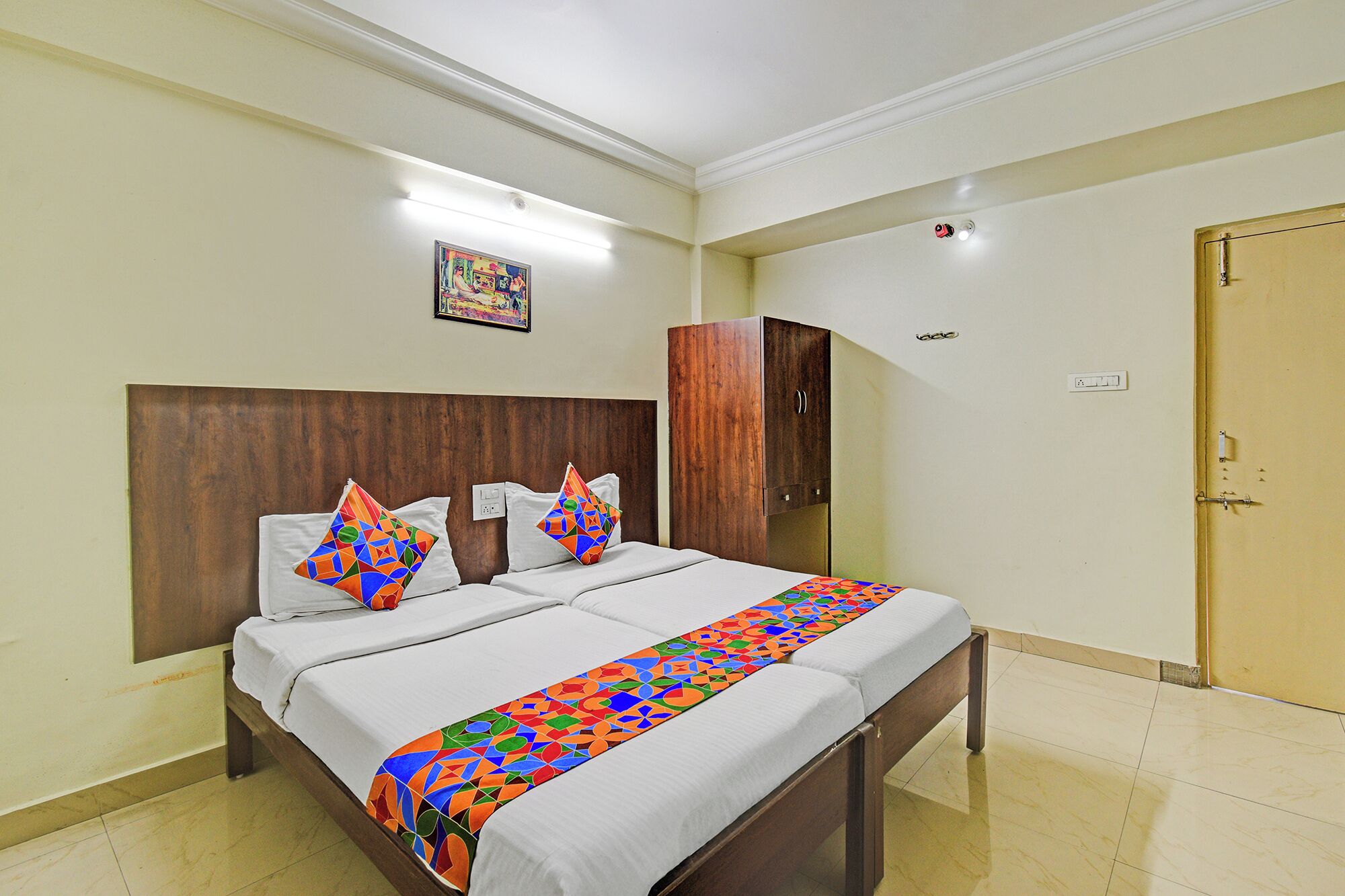 Una habitación de hotel con cama, armario, puerta y un cuadro en la pared.