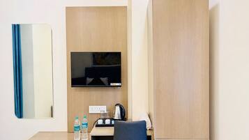 A hotel room with a desk, a flat-screen TV, a mirror, and a window.