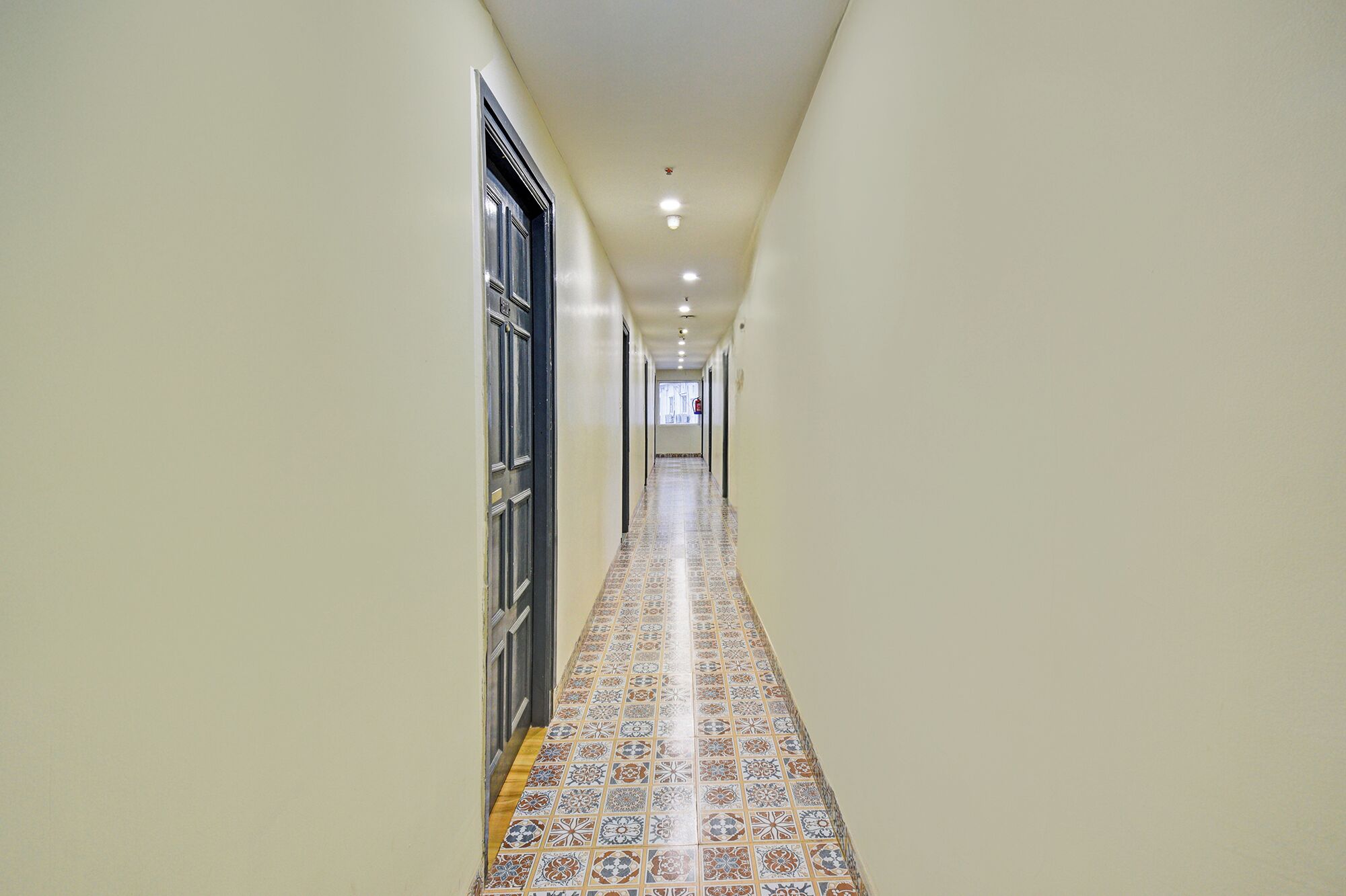 A narrow hallway with patterned floor tiles and a door on the left.