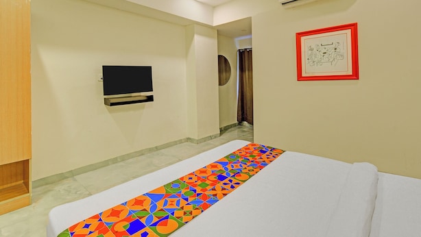 Une chambre d’hôtel avec un lit, un téléviseur fixé au mur et une œuvre d’art encadrée.