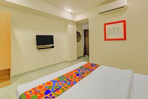 A hotel room with a bed, a television mounted on the wall, and a framed artwork. - FabHotel AM Castle - Nr ESI Hospital Metro Station (Hyderabad)