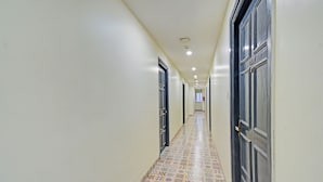 Un couloir avec des carreaux de sol décorés, des portes de part et d’autre, et un éclairage encastré.