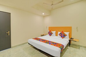 A hotel room with a bed, a nightstand, a telephone, a ceiling fan, and a door. - FabHotel AM Castle - Nr ESI Hospital Metro Station (Hyderabad)