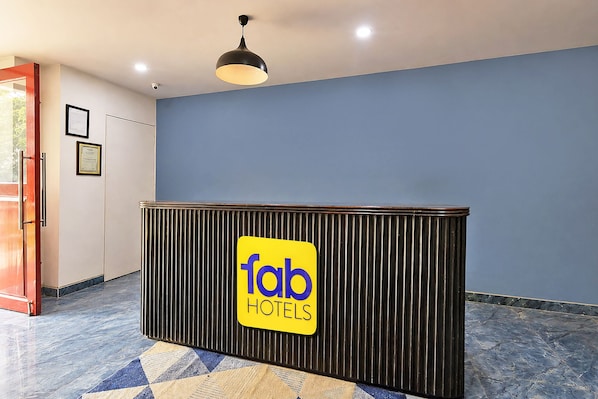 Una recepción con un cartel de 'fab hotels', una lámpara en el techo y un piso estampado.