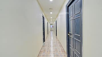Um corredor com ladrilhos estampados, uma porta escura à direita e uma parede de cor clara.