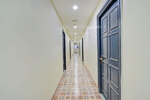 Un pasillo con baldosas de diseño, una puerta oscura a la derecha y una pared de color claro.
