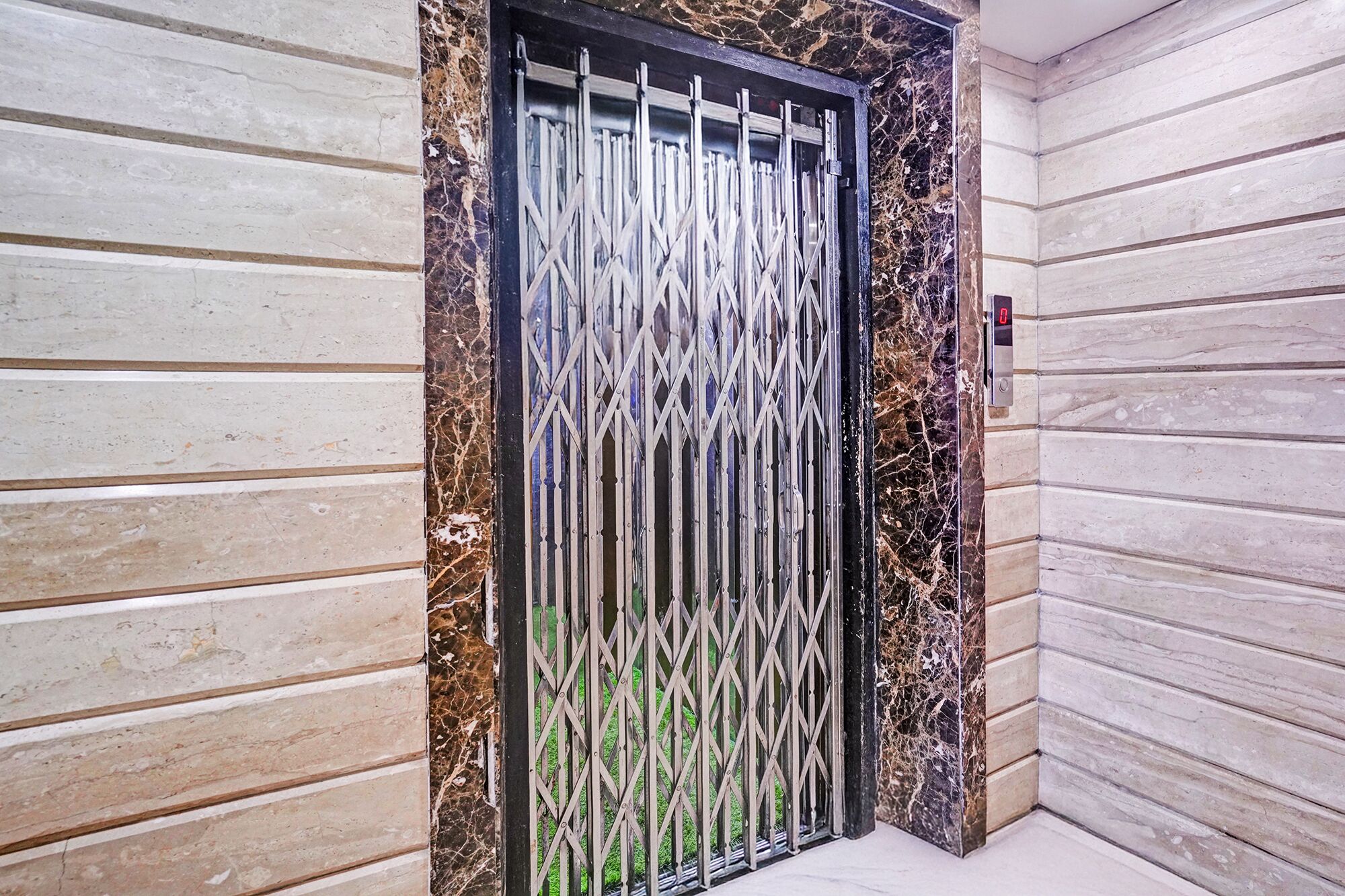 A door with a metal gate, a marble-like textured wall, and a corner with a light-colored floor.