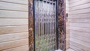Eine Tür mit einem Metallgitter, eine wandartige Oberfläche mit Marmorstruktur und eine Ecke mit hellem Boden.